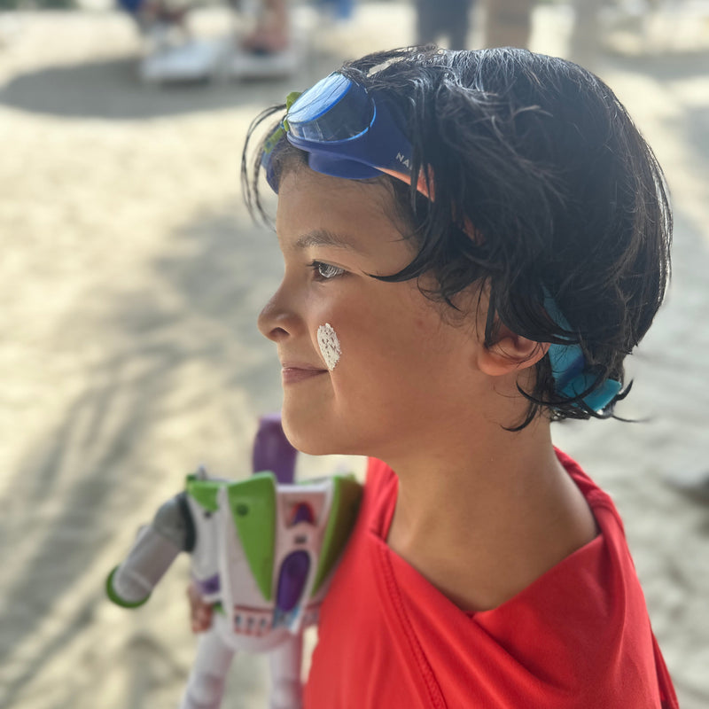 Una mano aplica crema solar en la nariz de un niño