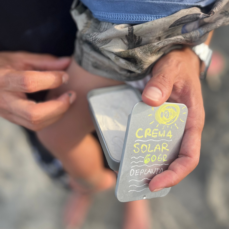 La lata de crema solar de 60 g, pintada a mano, en la mano de un niño