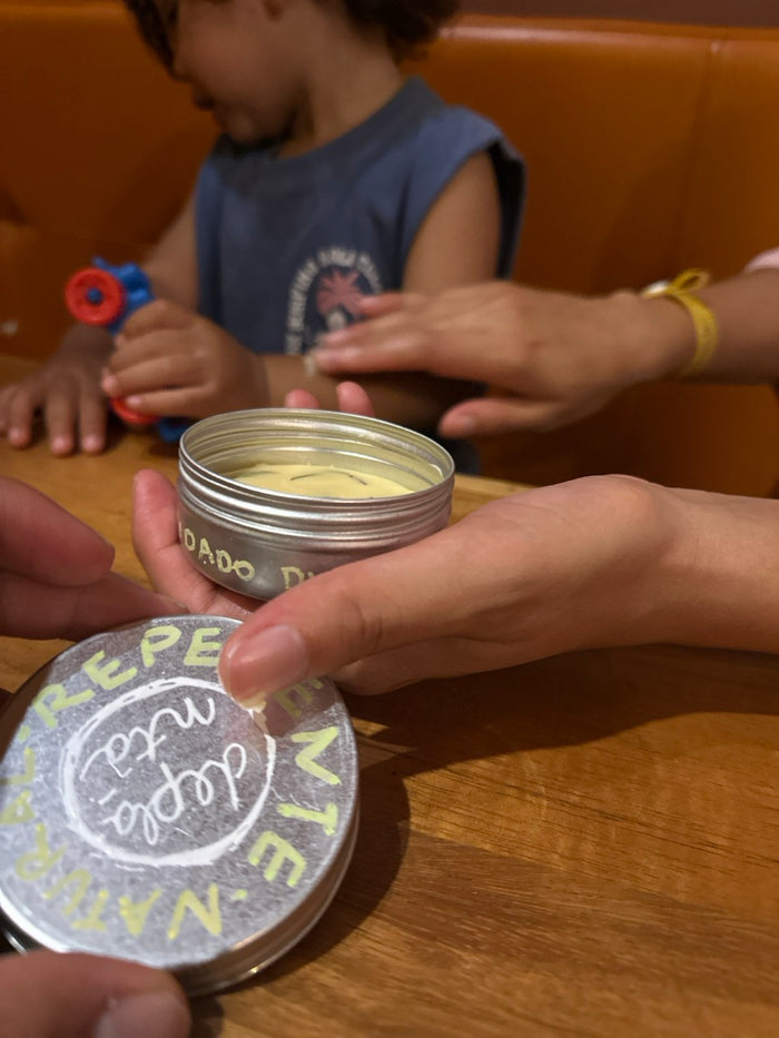 Una mano aplica repelente natural en el brazo de un niño