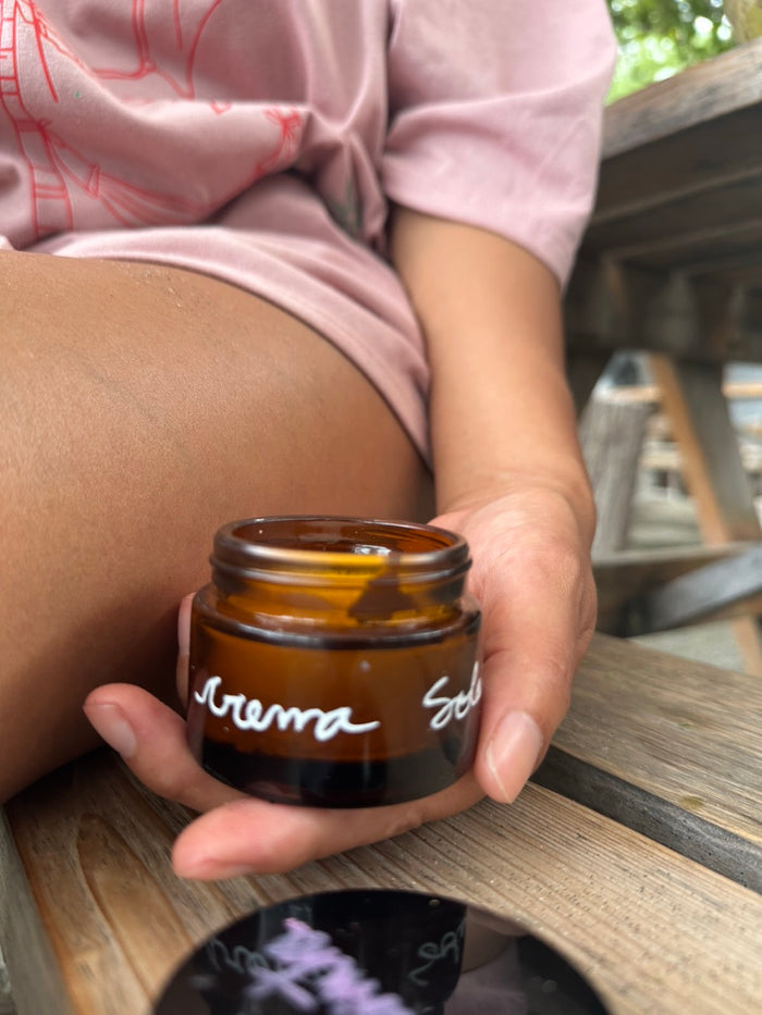 Crema solar en frasco ámbar en la mano