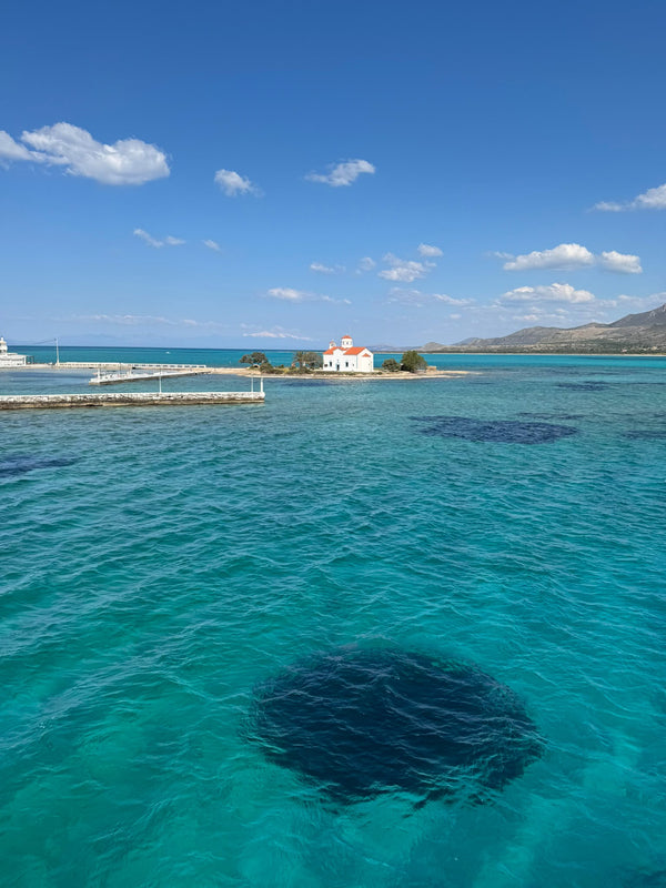 Una capilla blanca sobre un islote en medio del mar turquesa