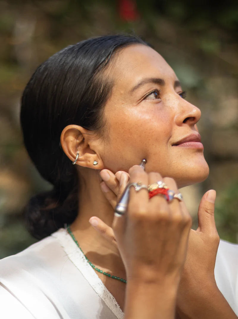 Gia se pasa la varita de reflexología facial por la mandíbula, con la mirada hacia arriba